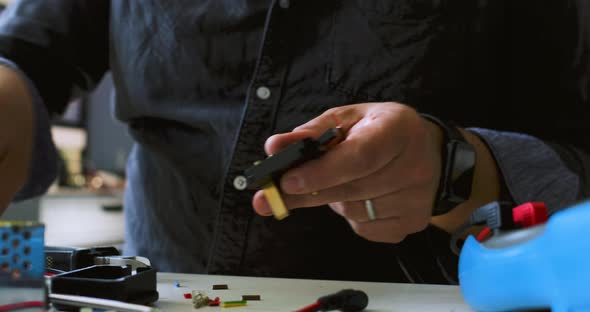 Male electrical engineer working from home during Coronavirus lockdown, attaching plug to electric c