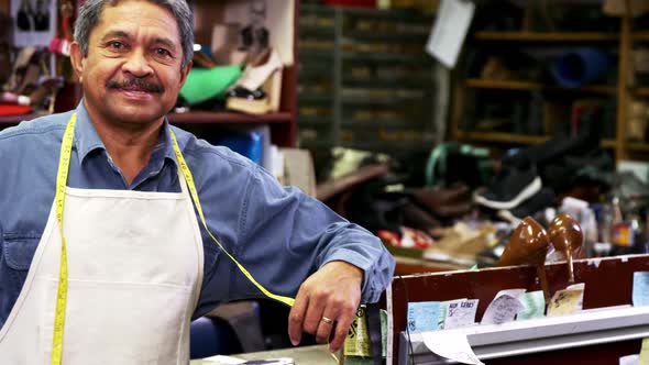 Smiling shoemaker leaning in workshop