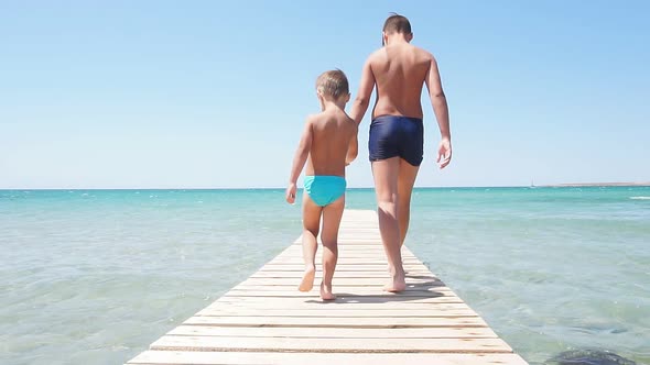 Children, Boys Walk Along the Pier To the Sea, the Pier Against the Background of the Azure Sea and