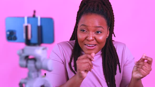 Dark Skinned Woman Laughing and Shooting Social Media Stories in Pink Wall Background