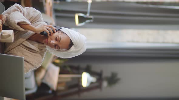 Woman Speaking on Phone and Working on Laptop at Home