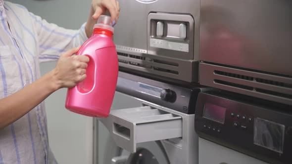 A Woman Pours Washing Powder Into a Washing Machine in a Public Laundry