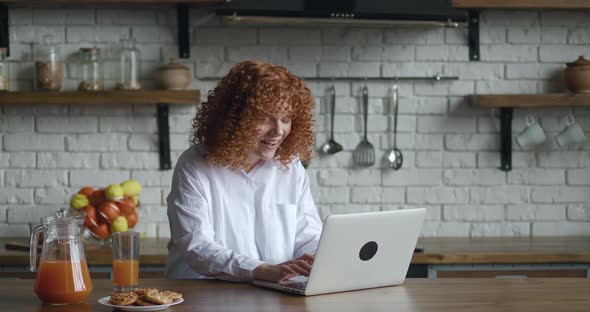 Young Redhaired Woman with Curly Hair Sitting at Home Kitchen Getting and Reading Congratulations