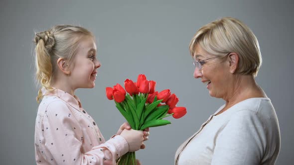 Happy Girl Giving Flowers to Grandmother, Family Tradition, Holiday Celebration