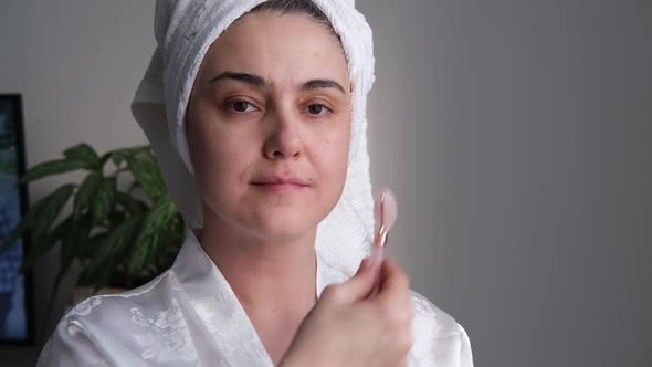 A Closeup Photo of a Young Woman Looking Relaxed and Smiling Doing a Massage with a Face Roller Made