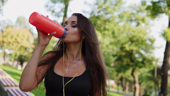 Sweating Woman Listening to the Music and Drinking Pure Water From the Bottle Refreshing Herself