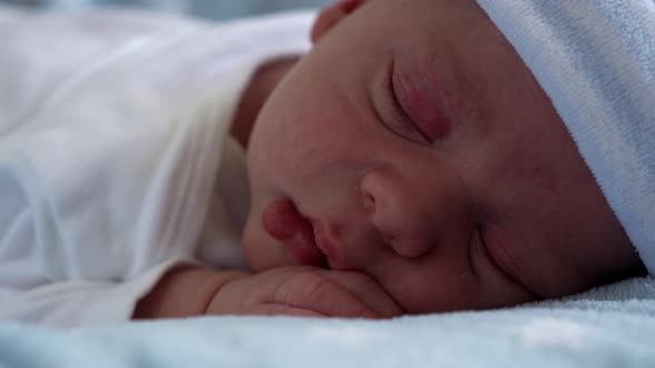 Closeup of Newborn Baby Face Portrait Early Days in Macro Sleeping On Blue Star Background