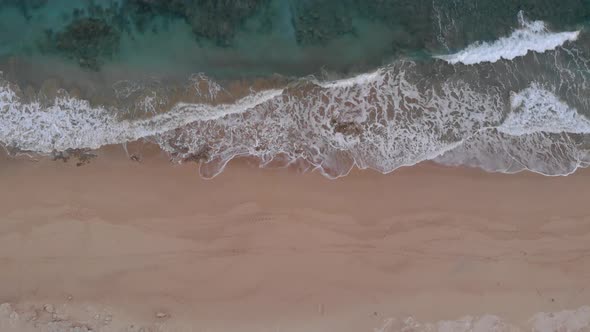 Aerial top-down lowering over waves crashing on Matadouro beach, Portugal