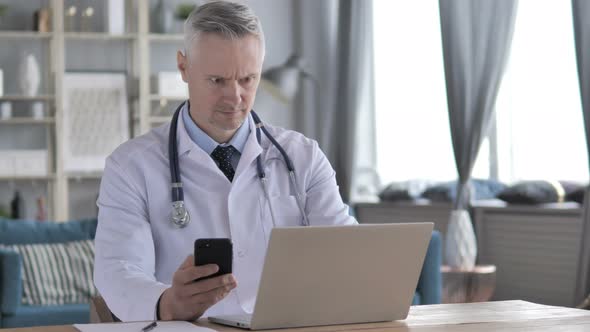 Doctor Working on Laptop and Using Smartphone in Clinic