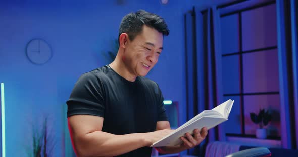 Asian Man in Sportswear which Reading Interesting Book During Exercising on Running Track