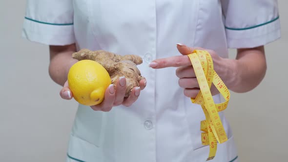 Nutritionist Doctor Healthy Lifestyle Concept - Holding Ginger Root, Lemon Fruit and Measuring Tape alt