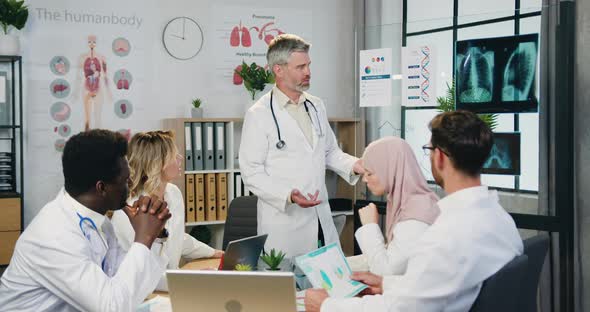 Multicultural Doctors Working Together During Discussion About Patient's X-ray Scan and Diagnosis