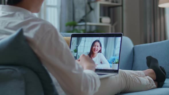 Man Having Video Call With A Woman On Laptop While Lying On Sofa In The Living Room