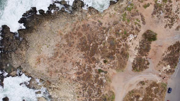 Drone top view waves break on rocks in a blue ocean. Sea waves on beautiful beach aerial