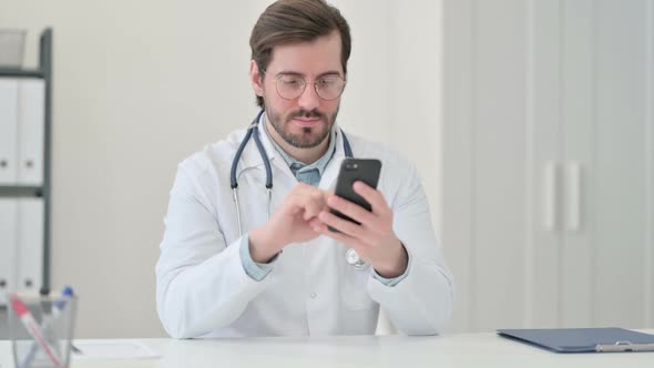 Young Male Doctor Using Smartphone at Work
