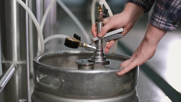 A Male Brewer Connects a Keg To a Beer Tank and Fills It with Beer. Close-up.