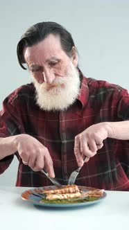 Senior Man Eating Steak of Fish at Home