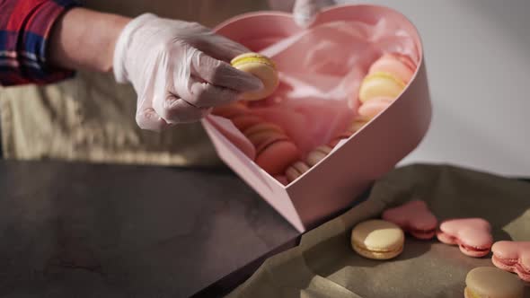 Woman in Gloves Puts Macaroni in Gift Box From Tray