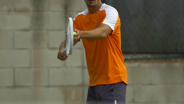 Male tennis player serving during match.