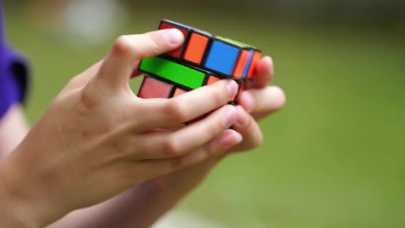 Boy practices with difficult Rubik's Cube. Smart teenager solving puzzle game with new Rubik's cube