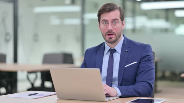 Serious Young Businessman with Laptop Feeling Shocked