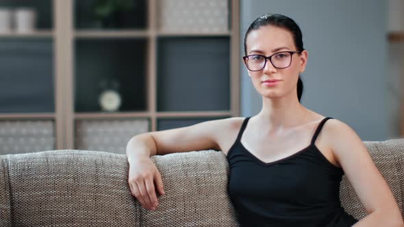 Portrait of Domestic Young Brunette Woman Sitting on Comfy Couch Relaxing at Home Medium Closeup