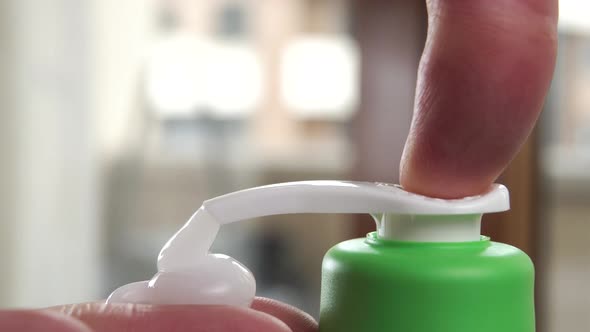 Man push dispenser of antibacterial liquid soap, squeezes in to disinfect his hands and body