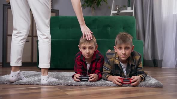 Teen Brothers Lying on the Floor and Playing Video Games Using Gamepads