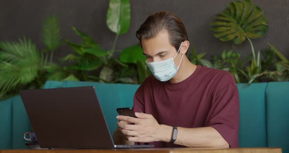 Young Man Wearing Protective Mask Sitting in Coffee Shop