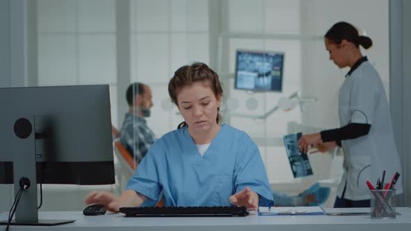 Dental Assistant Using Computer and x Ray Scans at Desk