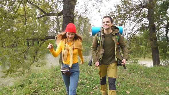 Young Couple Tourists with a Backpacks Walk Through a Forest Road.