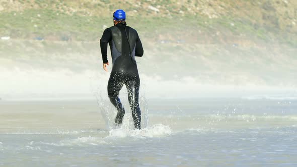 Rear view of male surfer running in the beach