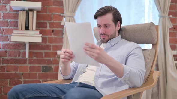 Casual Young Man Reacting to Loss on Documents Sofa