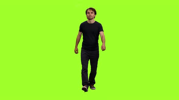 Casual Man in Black T-shirt Walks on Green Background