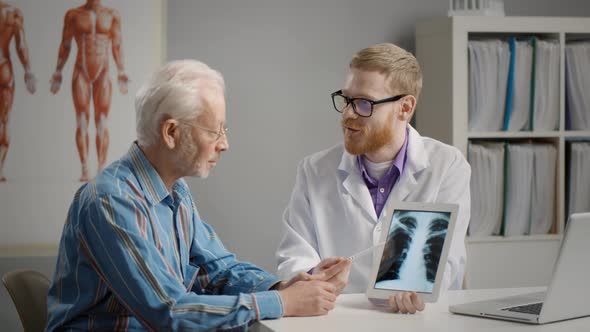Doctor Shows Results To Old Patient X-ray of the Lungs at Office in Modern Hospital