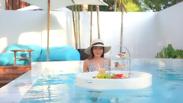 Woman with floating breakfast in pool