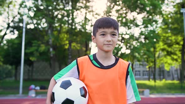 Football Player in Orange Vest Standing with Ball on the Outdoors Sport Field