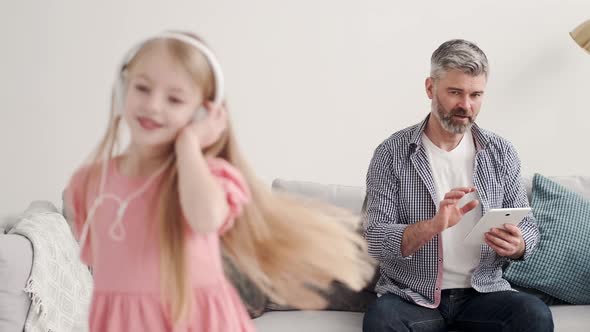 Little Girl Listening Music in Headphones with Grandfather