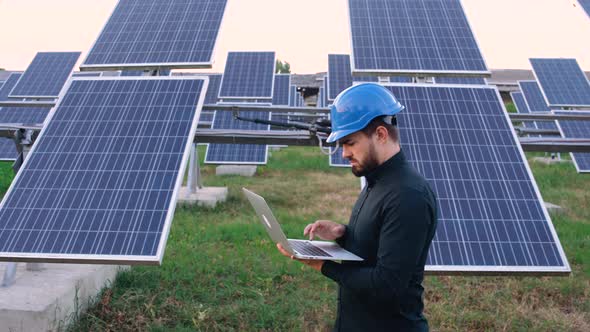 Successful Young Engineer with a Laptop in His Arms Who Plans To Expand the Plant with Solar Panels.