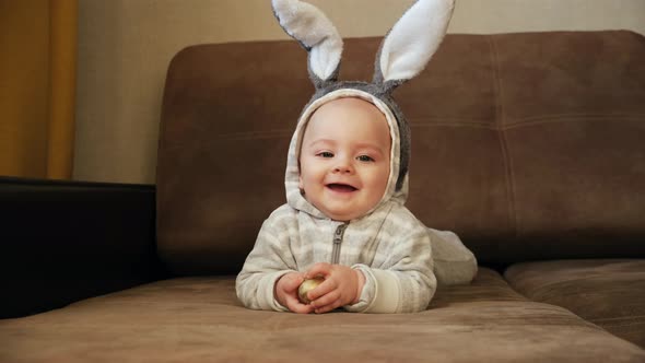 Cute Little Baby with Bunny Ears Smiling Holding Easter Egg