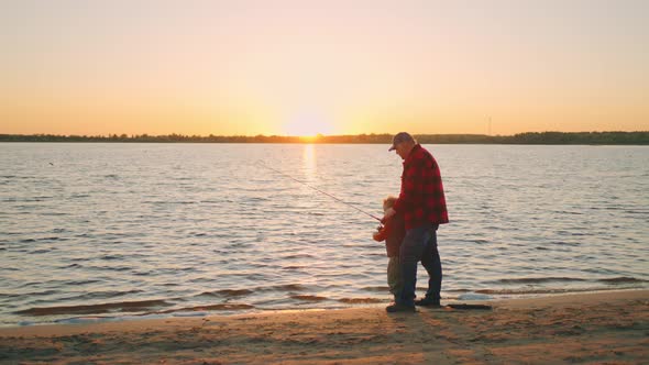 Happy Joint Pastime of Grandpa and Grandson in Nature Old Man and Little Boy are Fishing on River