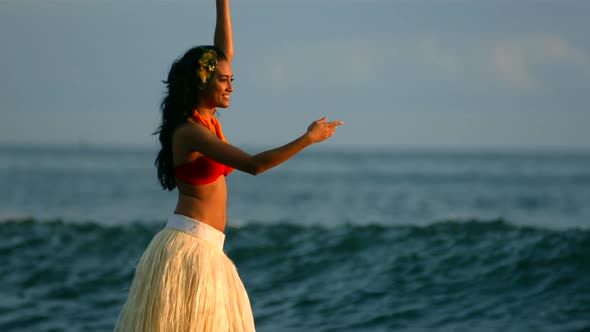 Hula dancer performs by ocean waves, slow motion