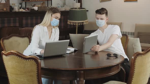 Social distance. Online Work. Freelancer. Couple in a cafe during quarantine.