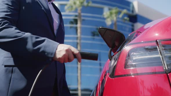 Businessman Connecting Electric Car and Waiting for Battery Charging at Office