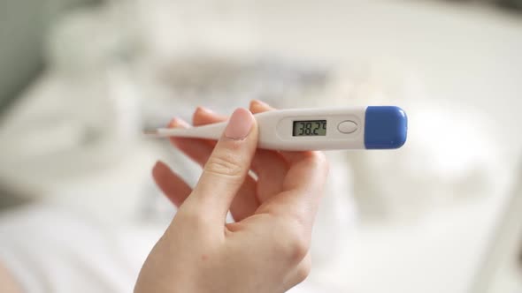 Male Hands Holding a Digital Thermometer with High Temperature