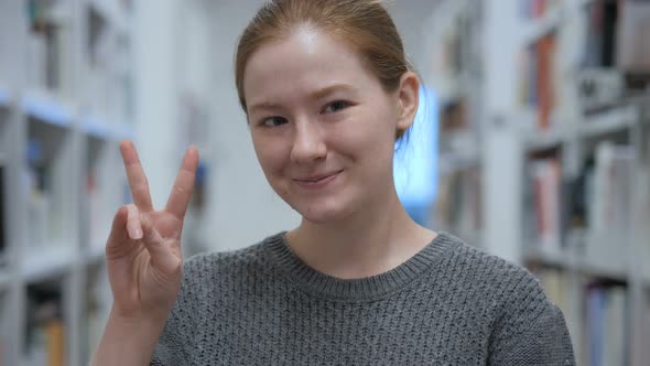 Portrait of Young Woman Gesturing Victory Sign in Cafe