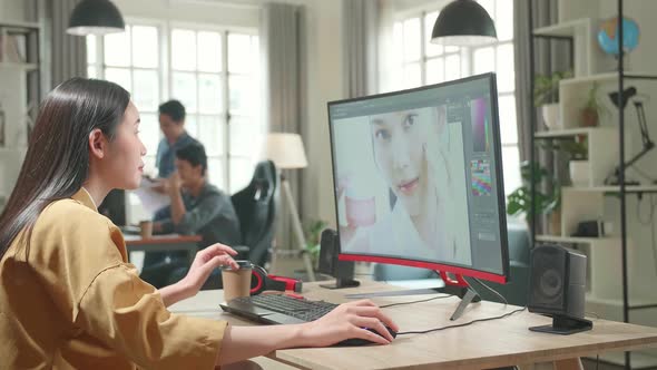 Female Digital Editor Drinking Coffee While Works In Photo Editing Software On Her Personal Computer