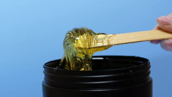 Sugar paste or honey wax for hair removal, dripping from wooden wax sticks - depilation and beauty.