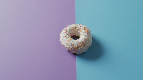 Video of donut with icing on purple and blue background