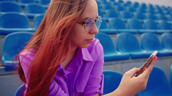 Focused Woman Using Mobile Phone on Tribune